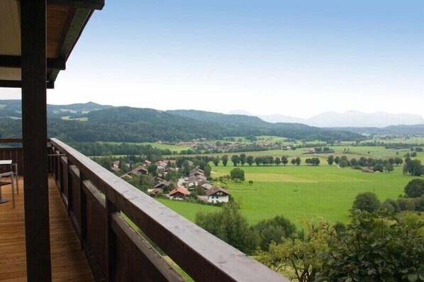 A wooden deck with a view of a rural landscape, including houses and green fields. - Ferienwohnung 6 "Untersberg", Nichtraucher, 2 Schlafzimmer, Sat-TV, 4 Sterne, max. 6 Personen (Anger)