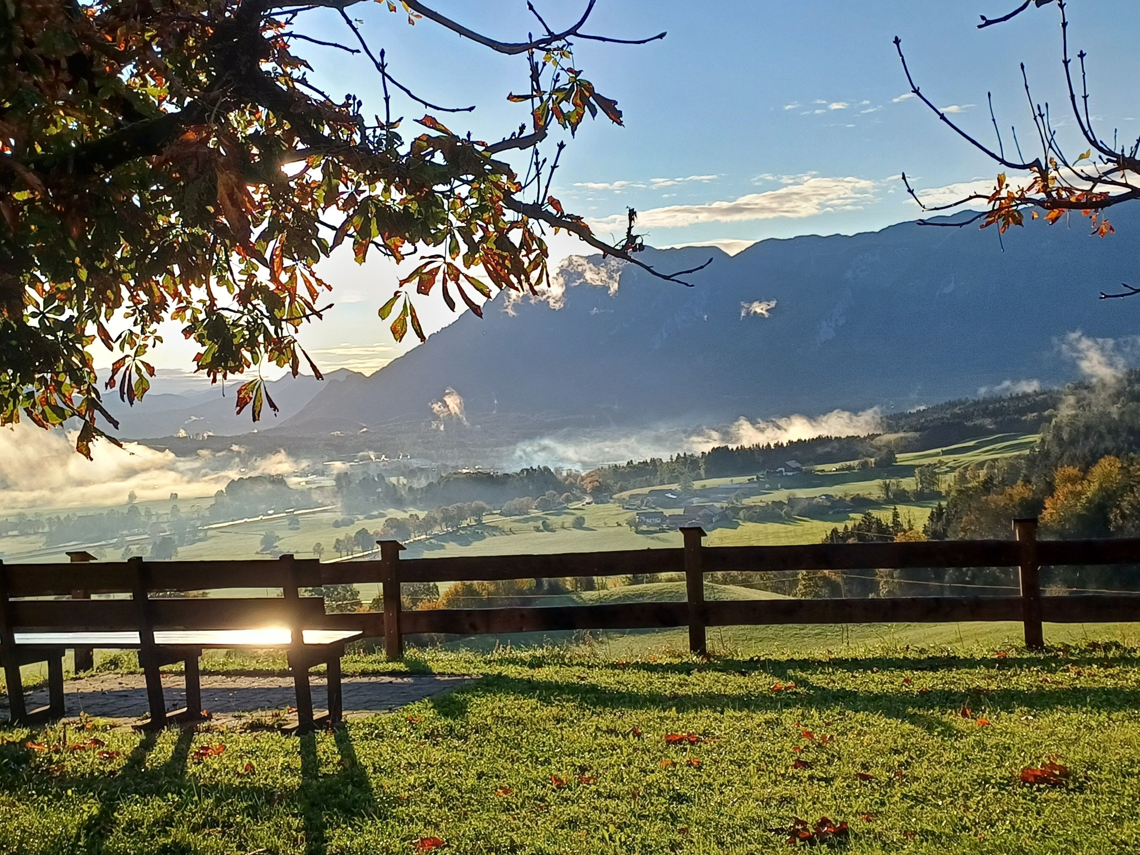 Une vue pittoresque d’un paysage montagneux, avec une clôture en bois et un banc.