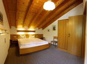 A bedroom with a wooden ceiling, a bed, a wardrobe, and a chair. - Two-room apartment Hausberg, 70 sqm, kitchen, bathroom and balcony (Reit im Winkl)