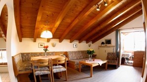 Um quarto acolhedor com teto de madeira, uma mesa de jantar com cadeiras, um sofá e uma pequena mesa de centro.