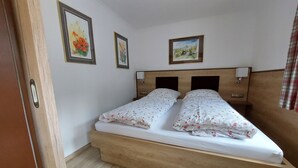 Ein Doppelbett mit blumigem Bettzeug, ein Holzkopfteil und zwei gerahmte Bilder an der Wand.