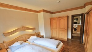A double bed with wooden headboard and nightstands, a wardrobe, and a hallway leading to a bathroom.
