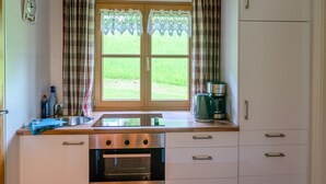 A kitchen with a window, a stove, and a refrigerator. - Apartment Staufenblick for - 2 persons, 50 sqm, balcony with unobstructed view of the mountains (Bad Reichenhall)
