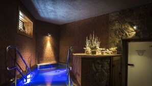A spa area with a hot tub, stone walls, and a wooden door labeled "Spa Room." - Hotel KATERAIN (Opava)