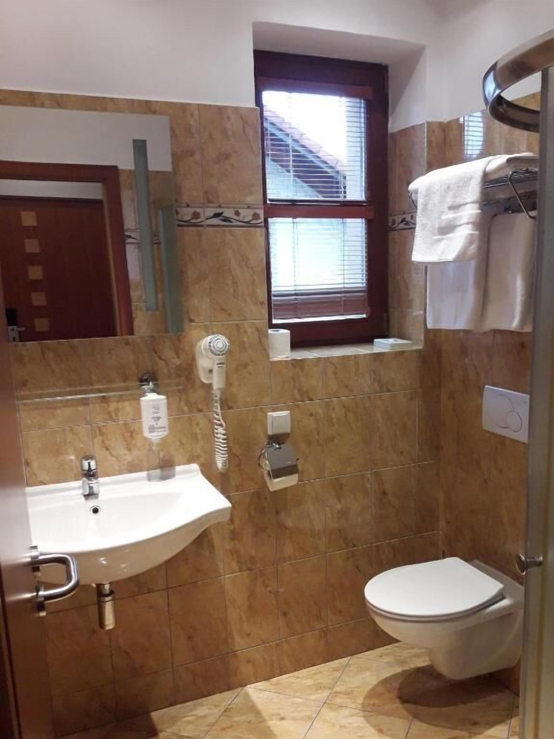 A bathroom with a sink, toilet, and a window with blinds.