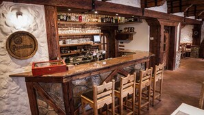 A rustic bar area with wooden bar counter, stone walls, and a variety of bottles and glasses. - Hotel KATERAIN (Opava)