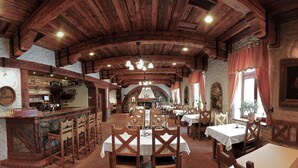 A rustic restaurant with wooden beams, stone walls, and a bar area. Tables and chairs are arranged for dining. - Hotel KATERAIN (Opava)