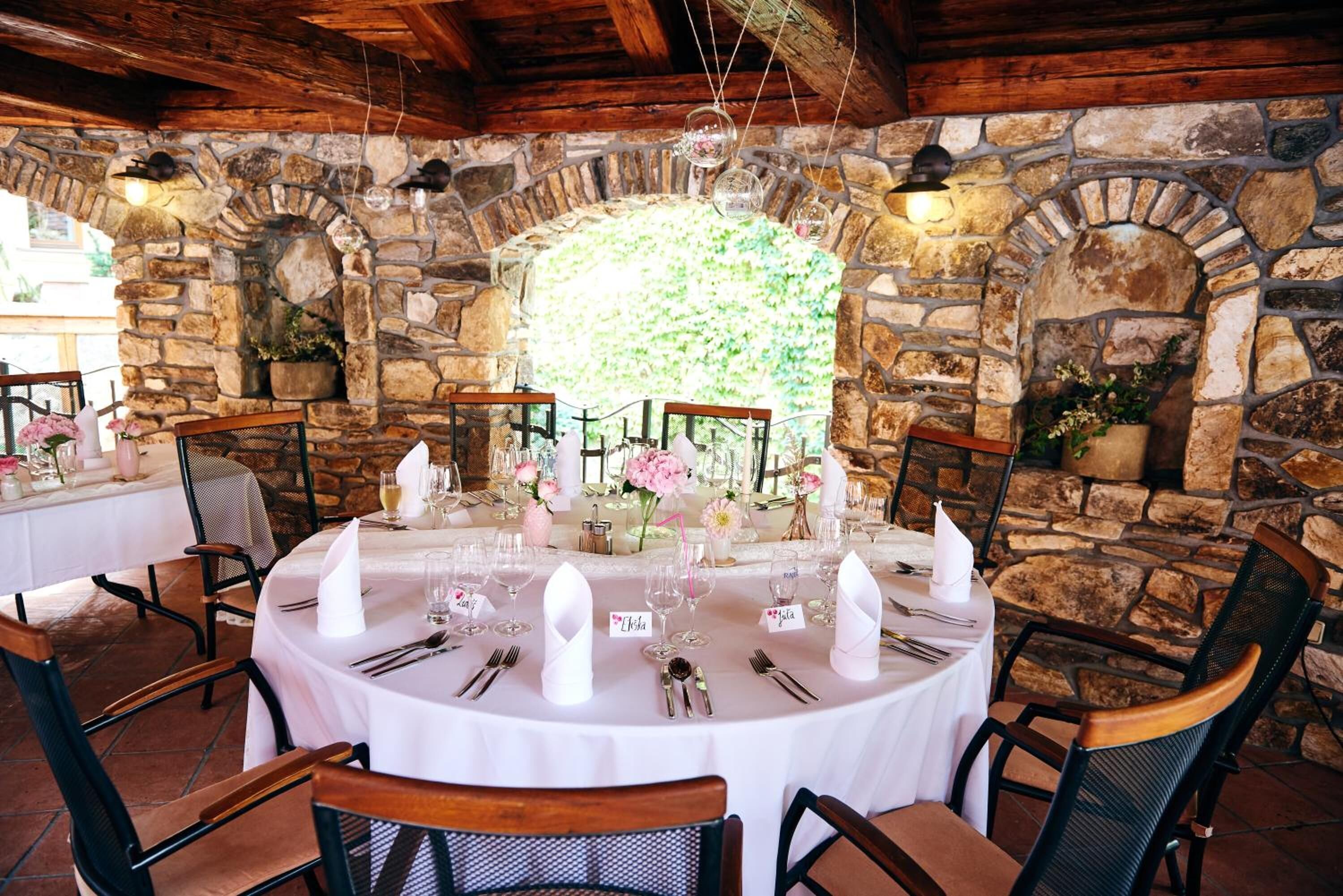 A round table set for two with white tablecloths, silverware, and glassware.