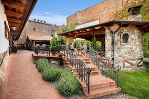 A courtyard with outdoor seating, stone steps, and a rustic building facade. - Hotel KATERAIN (Opava)