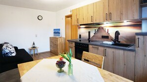 Une cuisine moderne avec des meubles en bois, une cuisinière et un coin repas avec une table mise pour deux personnes.
