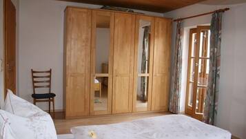 Ein Schlafzimmer mit einem Holzschrank, einem Bett, einem Stuhl und einem Fenster mit Vorhängen.