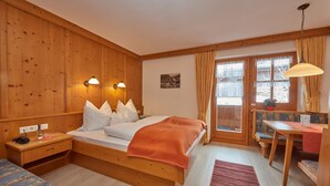A wooden room with a bed, bedside table, and a window with curtains.