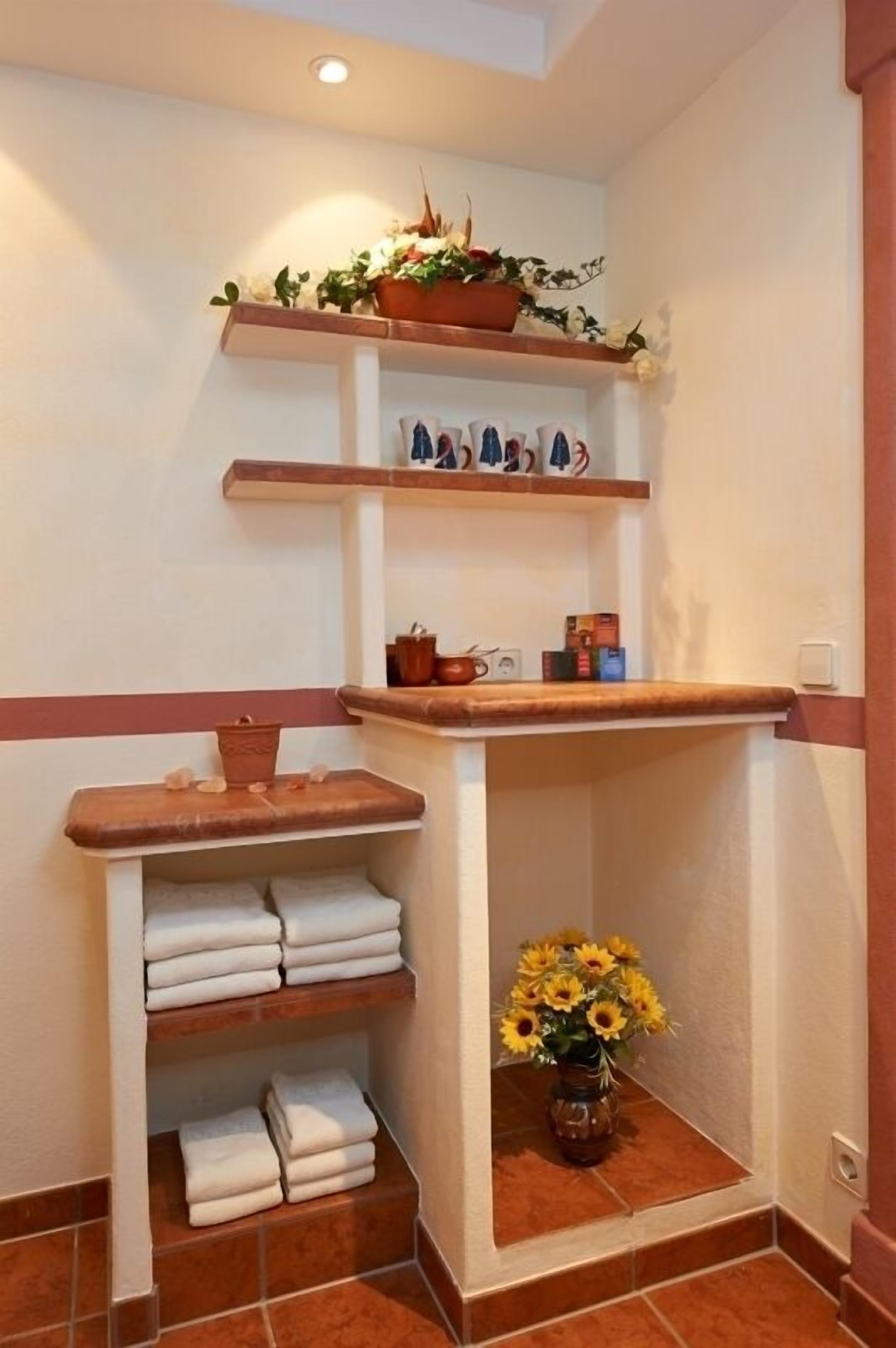 Un baño con repisas que sostienen toallas, una planta en maceta y un florero con flores.