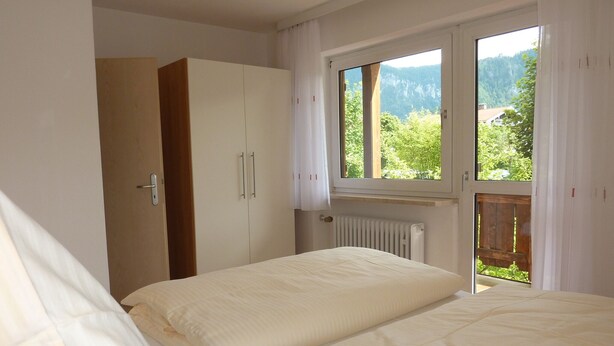 Ein Schlafzimmer mit zwei Betten, einem Kleiderschrank und einem Fenster mit Blick auf die Berge.