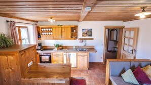 A rustic kitchen with wooden cabinets, a stove, and a sink. - Ferienwohnung "Wilder Kaiser" im Zuhäusl 72 qm mit drei Schlafzimmer und Balkon° (Sachrang)