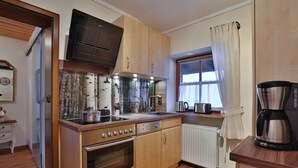 Une cuisine compacte avec des meubles en bois, un four encastré, un four à micro-ondes et une machine à café.