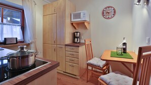 Une cuisine de taille réduite, équipée d’une cuisinière, d’un four à micro-ondes et de meubles de rangement en bois.