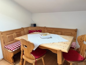 A corner dining area with a wooden table and bench, a radio, and a bowl of fruit on the table. - Apartment no. 16, 4-6 persons, 85 sqm, 3 bedrooms, extra bathroom, balcony (Schönau am Königssee)