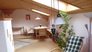 Tunnelmallinen ruokailutila, jossa on puinen pöytä, tuolit ja riippuvalaisin.