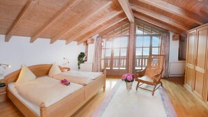 Ein Schlafzimmer mit einem hölzernen Bett, einem Sessel und einem großen Fenster.