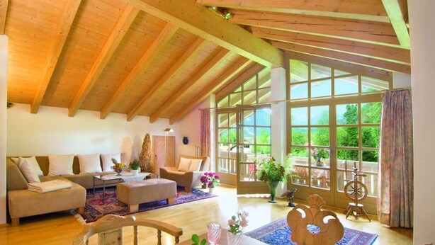 Ein geräumiges Wohnzimmer mit Holzbalken, einem großen Fenster und einer gemütlichen Sitzecke.