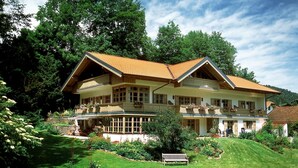 Ein großes, zweistöckiges Haus mit geneigtem Dach, mehreren Balkonen und einem gepflegten Garten.
