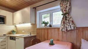 A compact kitchen with a sink, cabinets, and a window with curtains. - Ferienwohnung Nr.2 für 2-4 Personen (Berchtesgaden)
