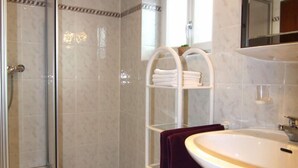 A bathroom with a glass shower enclosure, a white sink, and a marble-tiled floor. - Ferienwohnung Nr.2 für 2-4 Personen (Berchtesgaden)