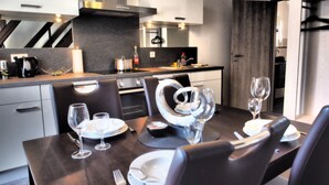 A modern kitchen with a dining area set for a meal. - Korkenzieher Restaurant Café (Briedel)