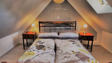 A bedroom with a sloped ceiling, two bedside tables with lamps, a bed with floral bedding, and a ceiling light fixture.