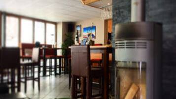 A restaurant with wooden tables and chairs, a large window, and a decorative wall piece.