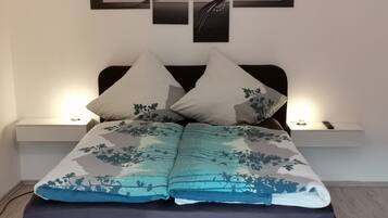 A bedroom with a bed, bedside tables, and wall art.