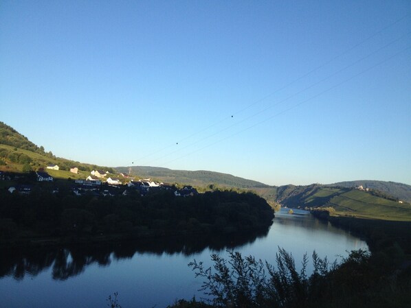 A calm lake surrounded by hills with houses in the distance. - Korkenzieher Restaurant Café (Briedel)