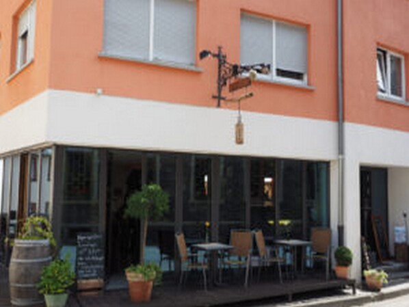 A building with a glass facade, outdoor seating area, and a signboard. - Korkenzieher Restaurant Café (Briedel)