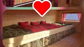 A cabin with a wooden interior, a window with red curtains, and a bed with red bedding.