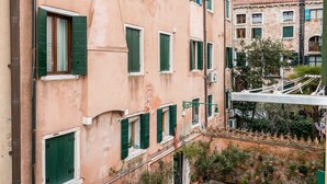Un edificio de varios pisos con contraventanas verdes y un balcón.