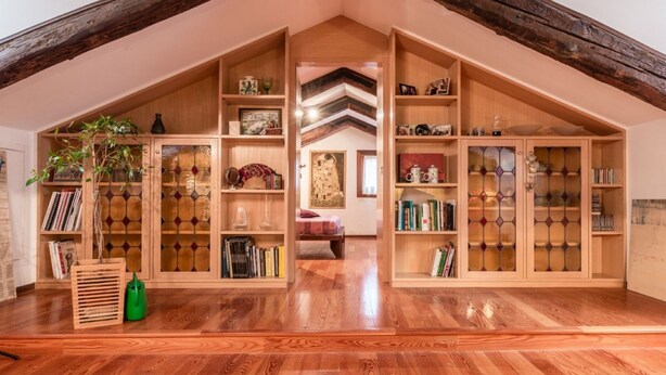 Un amplio ático con estanterías de madera, una escalera de madera y una planta verde.