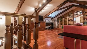 Amplio loft con vigas de madera, una escalera y un sofá rojo.