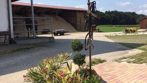Une étable avec un cheval, une pile de foin et un tracteur à l’arrière-plan.