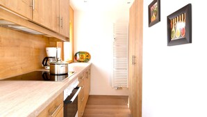 Une cuisine étroite avec des meubles en bois, une cuisinière et un plan de travail blanc.