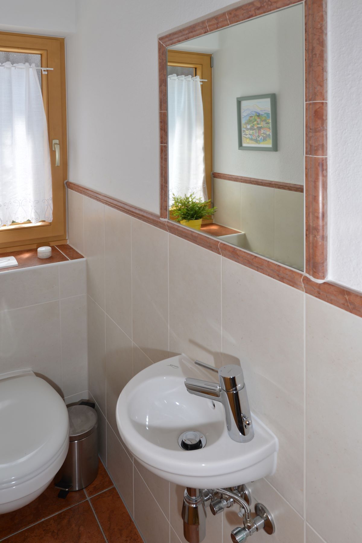 A bathroom with a white sink, a toilet, and a window with a curtain.