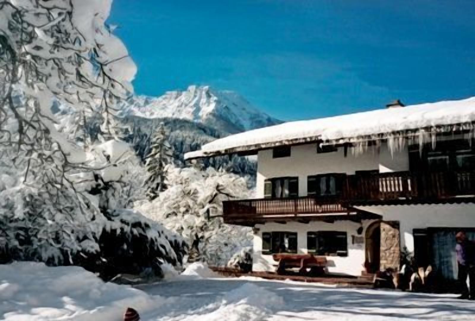 Eine Chalet mit Balkon, umgeben von schneebedeckten Bäumen und Bergen.