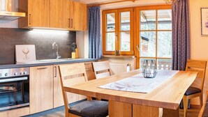 A modern kitchen with wooden cabinets, a built-in oven, and a dining area with a wooden table and chairs.