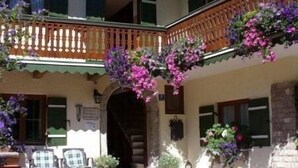 A two-story building with a balcony, stone steps, and outdoor seating.