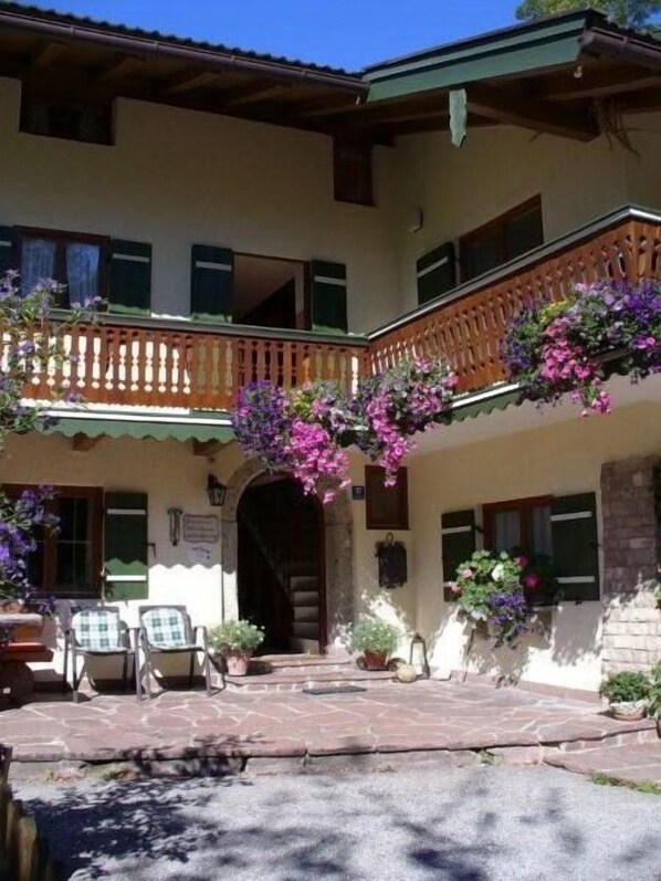 A two-story building with a balcony, stone steps, and outdoor seating.