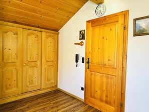 Une porte en bois avec un trou de serrure, un téléphone fixé au mur et une horloge.