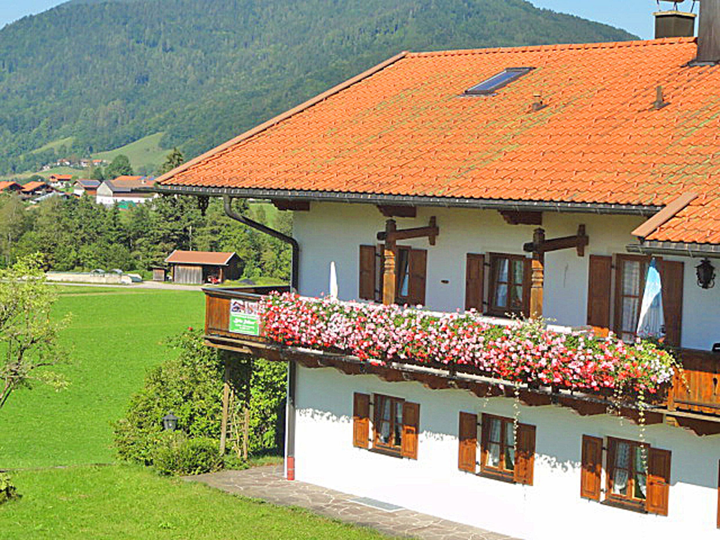 En traditionel chalet med røde tegltage, træpersienner og en balkon med blomsterkasser.