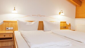 A neatly made bed with white linens, wooden headboard, and bedside tables with lamps. - (4) Giebelstüberl -1-Zimmer Appartement , ca. 30qm, 1-2 Personen, Wohn/Schlafraum, Kochnische, Balkon (Reit im Winkl)