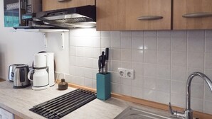 A kitchen with a microwave, toaster, coffee maker, sink, and a knife block. - Apartment Predigtstuhl 55 sqm for max. 3 persons, 1 bedroom, mountain view (Bayerisch Gmain)