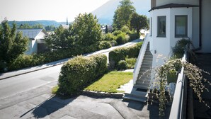 A residential building with a staircase leading to a porch, surrounded by greenery and a mountain in the background. - Apartment Predigtstuhl 55 sqm for max. 3 persons, 1 bedroom, mountain view (Bayerisch Gmain)